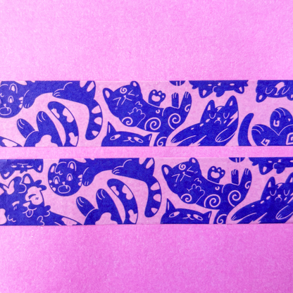 Two rolls of purple washi tape with blue cat designs on a pink background